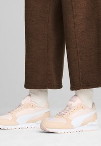 Sneaker rosa chiaro e beige con accenti bianchi, caratterizzati da una superficie liscia e testurizzata, punta rotonda e design con lacci.
