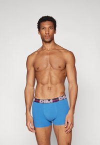 Blaue Baumwoll-Boxershorts mit einem kontrastierenden Bund, der ein rotes und weißes DIM-Logo trägt, enganliegendem Design und glatter Textur.