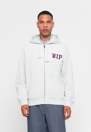 Graue Zip-Hoodie mit Kordelzug und lila "WIP"-Text auf der linken Brust. Hergestellt aus weichem Baumwollmaterial, entspannter Schnitt und mit Fronttaschen.