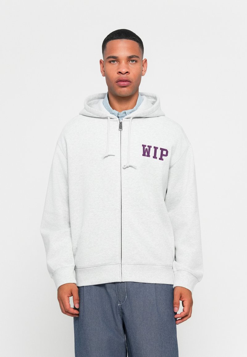 Gray zip-up hoodie with a drawstring and purple "WIP" text on the left chest. Soft cotton material, relaxed fit, and front pockets.