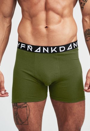 Olivgröna bomullsboxershorts med svart resår i midjan, prydd med vit text. Mjuk textur, figurnära design och längd till mitten av låret.