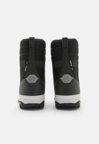 Botas aislantes negras con un upper acolchado, suela de goma y acentos reflectantes; cuentan con costuras verticales y una lengüeta en la parte posterior.