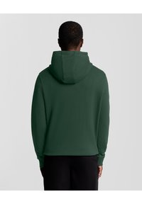 Felpa verde con cappuccio e maniche lunghe, realizzata in materiale morbido, con un taglio morbido e una tasca a marsupio sul davanti.