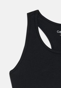 Top regata preto sem mangas com design de costas nadadoras, costura visível e etiqueta de marca branca parcial dentro do colarinho.