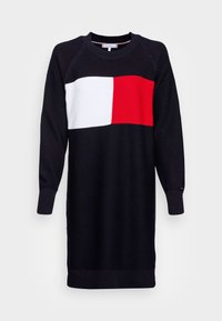 Dunkelblaues Strickkleid mit einem weißen und roten rechteckigen Block auf der Vorderseite. Mit gerippten Bündchen und Saum. Rundhalsausschnitt.