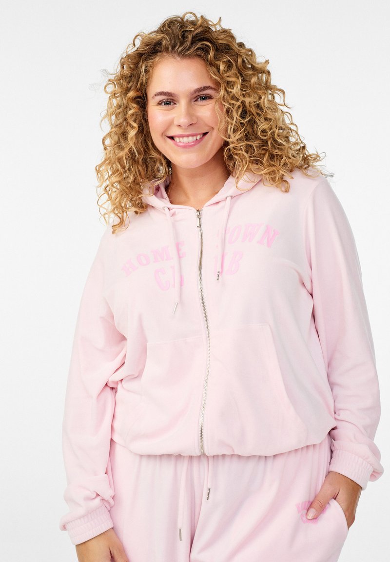Felpa con cappuccio rosa chiaro con cerniera, cappuccio con coulisse, tasche anteriori e scritta "HOMETOWN CLUB" in rosa più chiaro. Tessuto morbido e vestibilità comoda.