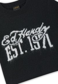 Pull en maille noire avec texte blanc « Ed Hardy Est. 1971 » sur la poitrine et une petite étiquette noire cousue à l'intérieur du col.