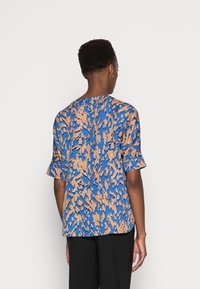 Top a righe blu e beige con maniche corte e vestibilità comoda, realizzato in un tessuto leggero e morbido.