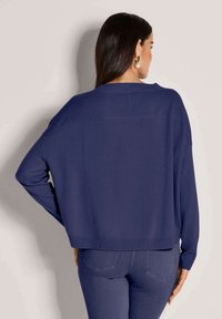 Marineblaues, übergroßes Strickpullover mit Rundhalsausschnitt und überschnittenen Schultern. Glatte Textur und gerippter Saum, cropped Länge.