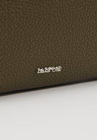 Sac à main en cuir texturé vert olive avec un logo "Parfois" argenté sur une surface élégante. Design compact avec une finition lisse.