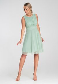 Miętowozielona, bezrękawnikowa sukienka w kształcie litery A z plisowanym topem i paskiem w talii. Lekki, zwiewny materiał z warstwową spódnicą. Minimalistyczny design.