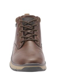 Hnedé kožené členkové topánky s okrúhlou špičkou, kontrastnou béžovou podrážkou a hnedými šnúrkami; hladký povrch s logom na jazyku.