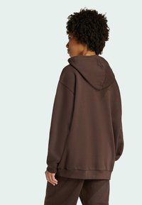 Sudadera con capucha marrón de corte relajado. Fabricada con tela suave, con un bolsillo tipo canguro y puños acanalados. Diseño minimalista.