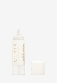 OSKIA London Adaptive Tan i en vit tub med guldtext. Har en spetsig applicator och ett vitt lock. Kompakt och stilren design.