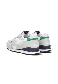 Sneakers atletici grigi con accenti bianchi e verdi, pelle texturizzata, pannelli in rete e suola nera. Presentano un tallone con marchio e lacci piatti.