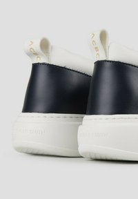 Marineblauwe en witte sneakers met een gladleren bovenwerk, voorzien van een getextureerde witte zool en reliëfbranding op de hak.