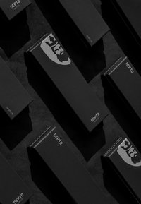 Black watch emballage har en mat finish med præget sølv logo accenter og minimalistisk tekst. Flere kasser arrangeret på en mørk overflade.