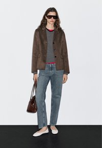 Brown wool blend blazer, striped long-sleeve shirt with red accents, light denim jeans, gray flats, and a brown leather handbag.