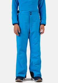 Pantaloni da neve blu brillante con un esterno liscio, chiusura a due bottoni e grandi tasche; polsini neri rinforzati e vestibilità comoda.