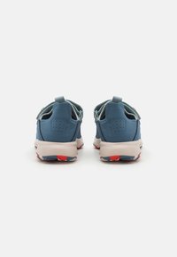 Blue athletic shoes with smooth upper material, padded collar, and contrasting white and red rubber sole. Features pull tabs on the heel.