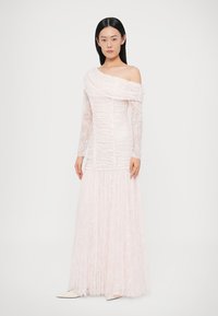 Różowa sukienka z opuszczonymi ramionami i długimi rękawami, wykonana z teksturowanej tkaniny z koronkowymi zdobieniami, z dopasowanym gorsetem i rozkloszowanym dołem.