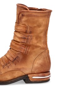 Stivale alla caviglia in pelle tan con multiple cinghie orizzontali, punta affusolata e un piccolo accent silver sul tacco. Texture liscia.