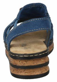 Sandale en tissu bleu avec des brides croisées, semelle intermédiaire en liège et semelle extérieure en caoutchouc noir. Présente des coutures visibles et une semelle intérieure texturée.