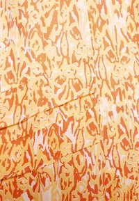 Stof med en levende gul bund og et abstrakt mønster i orange og hvidt. Designet har et tekstureret udseende med lagdelte sektioner.