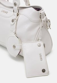 Borsa sintetica bianca con hardware argentato, forma arrotondata e superficie texturizzata. Include un portamonete rotondo e un porta-tessere rettangolare.