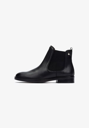 Des bottes Chelsea noires en cuir présentent une surface lisse, des panneaux élastiques sur les côtés, une languette en boucle et un talon bas empilé pour un design classique.