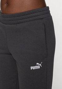 Pantaloni sportivi grigio scuro realizzati in misto cotone, con vita elasticizzata, tasche laterali e logo Puma bianco sulla coscia sinistra.