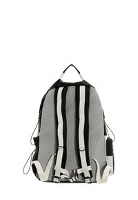 Mochila gris con detalles en negro y blanco. Cuenta con correas acolchadas, superficie texturizada y bolsillos laterales. Herrajes de correas ajustables visibles.