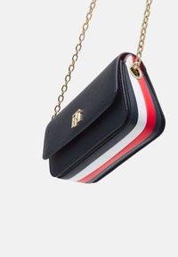 Borsa a tracolla in pelle nera con tracolla in catena dorata, finitura testurizzata e dettagli a strisce rossi, bianchi e blu sulla parte inferiore.