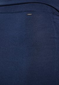 Tiefblaue Leggings aus einem glatten, dehnbaren Stoff. Verfügt über ein kleines metallisches Logodetail in der Nähe des Bundes an der Seite.