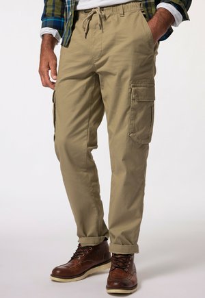 Beige cargo bukser med elastisk talje og snøre, med sidelommer og afslappet pasform. Bæres med brune snørebåndsstøvler.