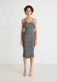 Robe midi en métal gris avec des bretelles spaghetti ajustables, un détail de fronces texturées et une silhouette ajustée, associée à des talons argentés à lanières.