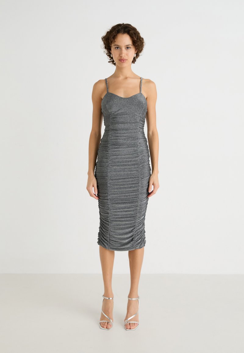 Robe midi en métal gris avec des bretelles spaghetti ajustables, un détail de fronces texturées et une silhouette ajustée, associée à des talons argentés à lanières.