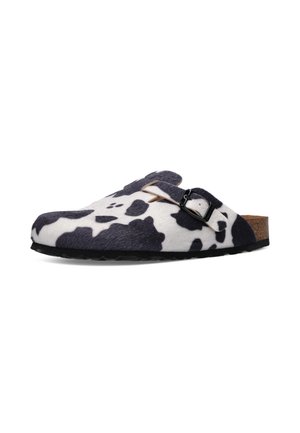 Sabot à enfiler avec imprimé vache noir et blanc, bride ajustable avec boucle, semelle intérieure en liège et semelle noire.