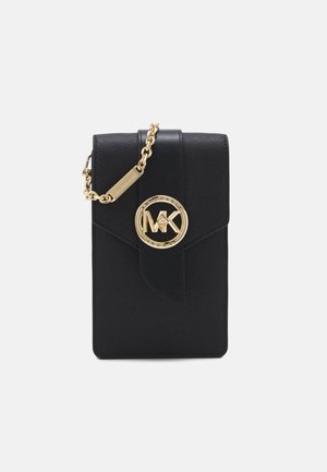 Portefeuille en cuir noir Michael Kors avec chaîne dorée et fermoir rond au logo MK sur le devant sur fond blanc.