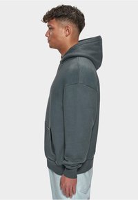 Koksgrå hoodie med kængurulomme, afslappet pasform, ribbede manchetter og hætte med snoretræk. Blød tekstur og minimalistisk design.