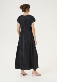 Mustmust pikk kleit lühike varrukatega, valge õmblusega, külgõmblustega ja sirge lõikega. Kanda koos roosade plokk-kontsaga sandaalidega.