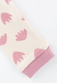 Cotton leggings with a cream base and pink leaf patterns, featuring a solid pink cuff at the bottom of the leg.