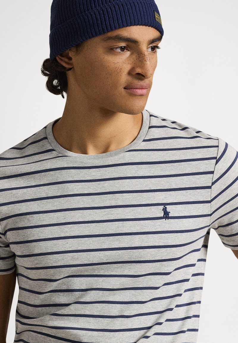 Grijs gestreept T-shirt met marineblauwe horizontale lijnen en een klein geborduurd logo op de borst. Ronde hals en korte mouwen.