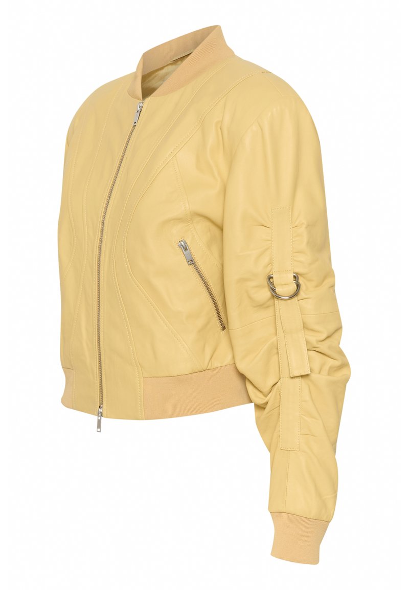 Veste bomber en cuir jaune avec fermeture éclair à l'avant, poche latérale zippée, poignets et ourlet côtelés, et détail en D-ring sur la manche.