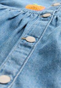 Denim jurk met oranje geborduurde ontwerpen, voorzien van zilverkleurige metalen knopen, geplooide stof bij de taille en een lichtblauwe textuur.