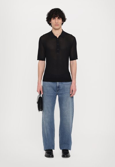 Fekete, textúrált, rövid ujjú poloing gallérral, gombos állítással. Világoskék, bő szárú farmernadrággal és fekete táskával párosítva.