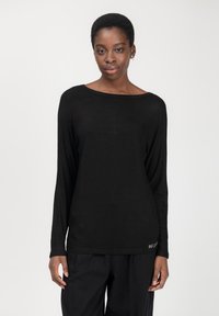 Top nero a maniche lunghe in tessuto leggero con scollatura ampia. Presenta una vestibilità rilassata e un sottile dettaglio del logo in vita.
