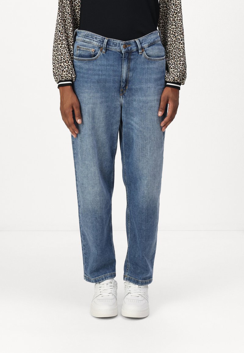 Lyseblå jeans med rette ben og en falmet finish, to frontlommer, glidelås og sølvfarget metallhardware. Bært med hvite joggesko.