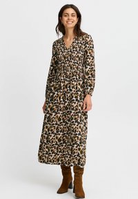 Långärmad, ankellång klänning i ett leopardmönster med nyanser av brunt, grönt och rosa. Har en V-ringning och smockad midja.