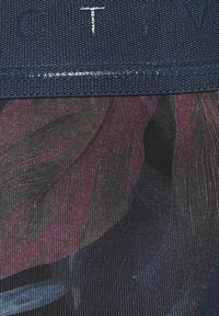 Floral-patterned fabric featuring dark tones with purple and blue accents, bordered by a textured navy band with embossed letters.